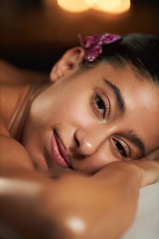A spa guest relaxing with an orchid flower in her hair after a treatment at Nuad Thai Massage Athens
