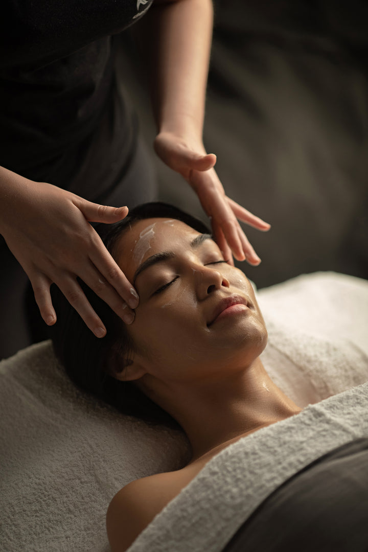 Therapist performing a facial massage with cream on a client's forehead