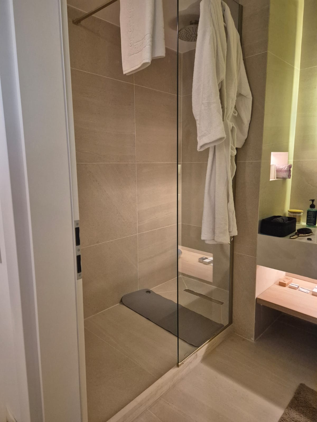 Glass shower cabin with bathrobes and toiletries in an Athens spa bathroom