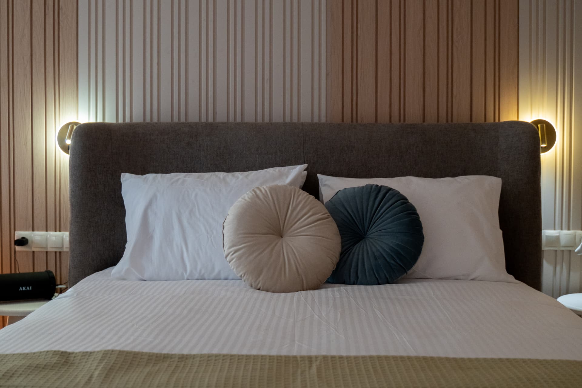 Retreat suite bed dressed in crisp white linens with round decorative pillows and warm accent lighting