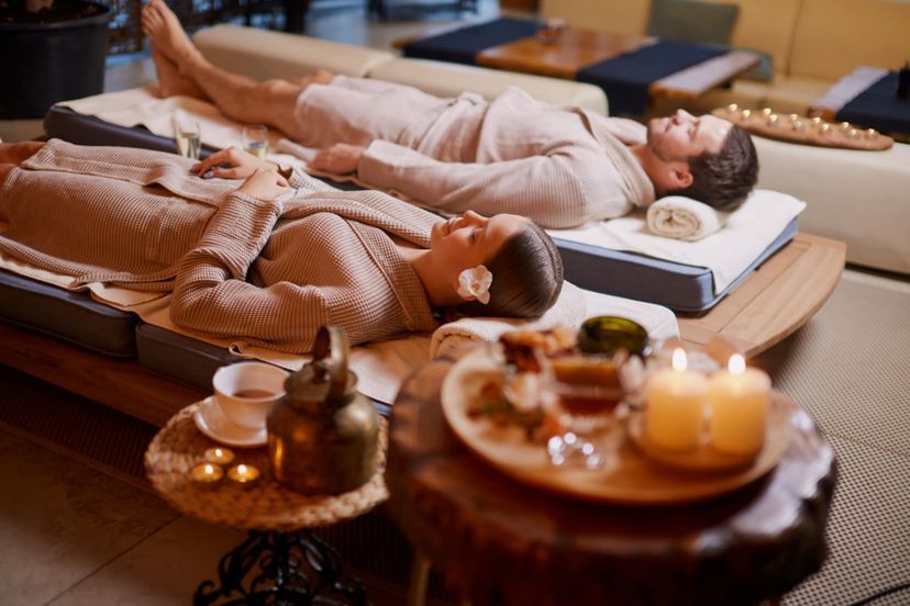 Couple in robes relaxing side by side on massage tables in a candlelit room