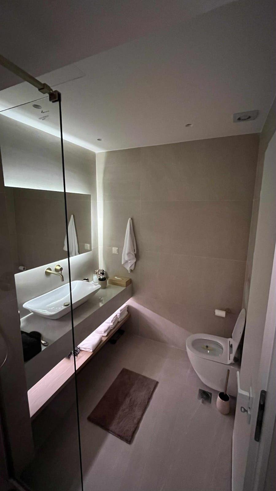 Clean private bathroom with sink, mirror and toiletries