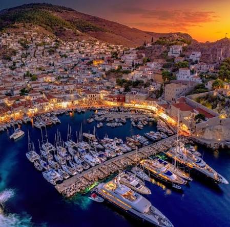The harbour of Hydra island at sunset, yachts in the port and the hillside town glowing — a favourite island day trip from Athens