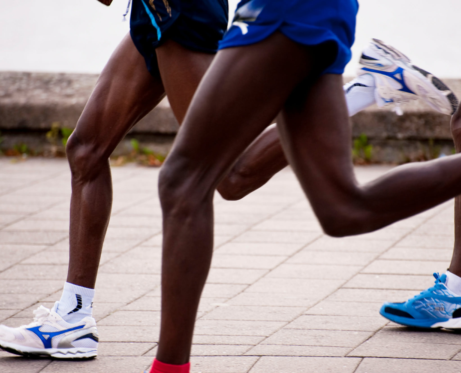 Close-up of marathon runners' legs striding on a paved street