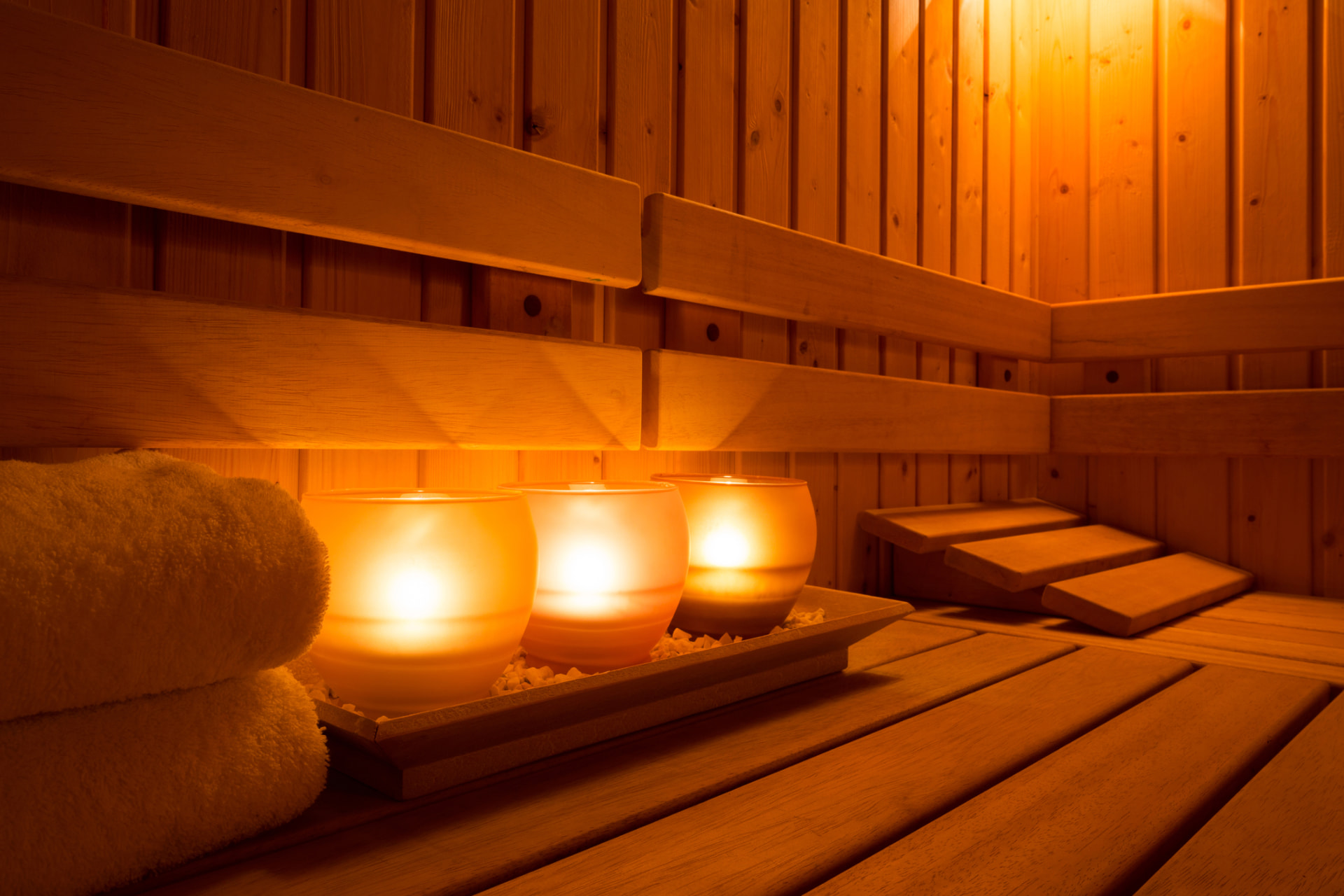 Warm wooden sauna interior with glowing candles and folded towels at Nuad Thai Massage Athens