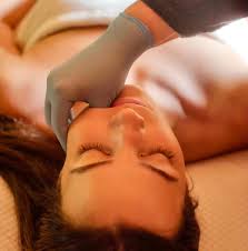Therapist performing a Gua Sha face and jaw massage for headache relief