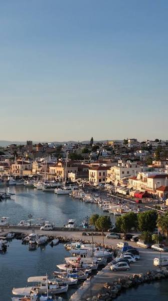 The port of Aegina island at golden hour with fishing boats and the hilltop town — an easy island day trip from Athens