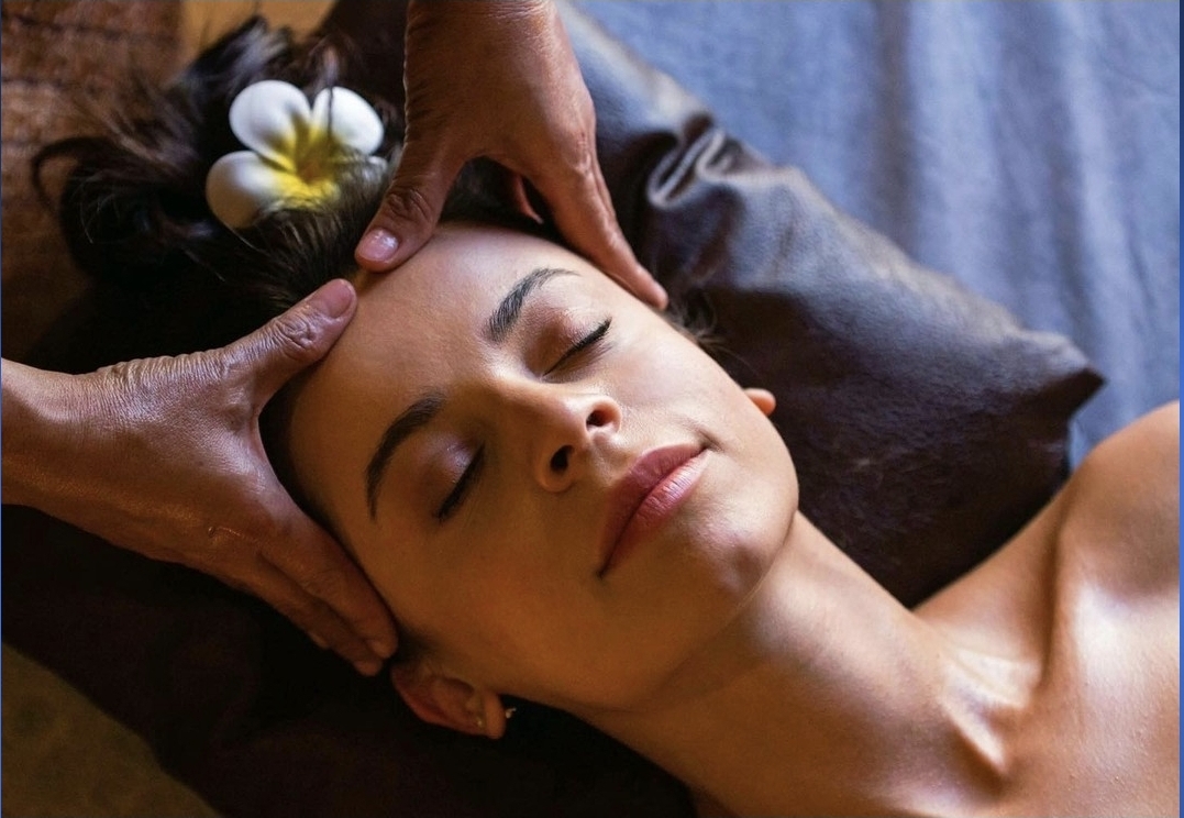 A guest with a frangipani flower in her hair receiving a relaxing head oil massage at Nuad Thai Massage Athens