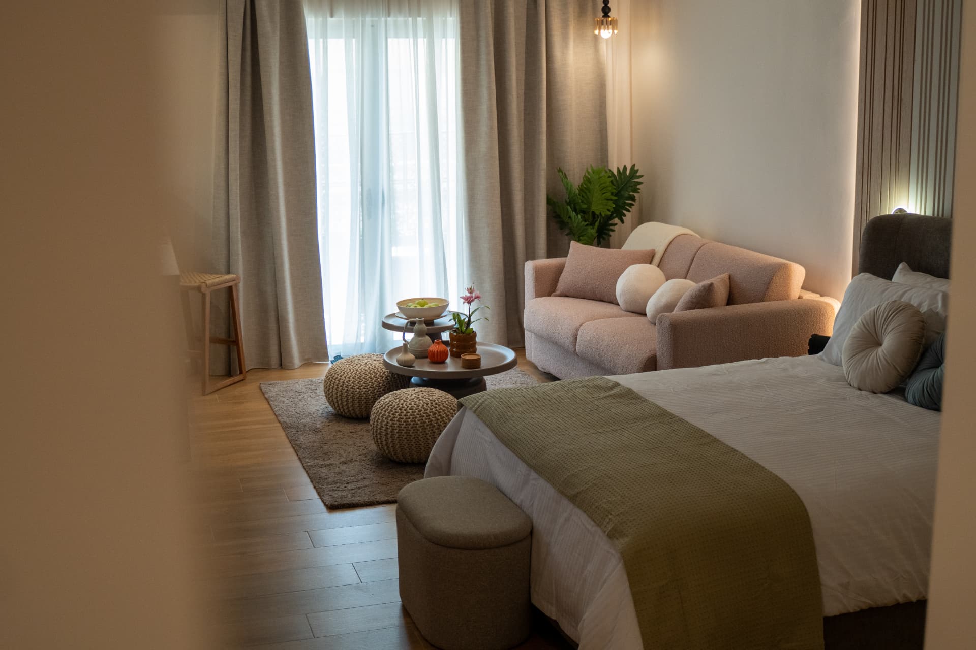 Spacious retreat suite living area with a soft sofa, woven poufs and balcony light in central Athens