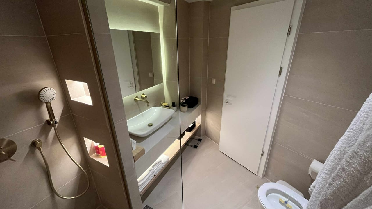Modern glass shower cabin with brass fixtures and fresh towels