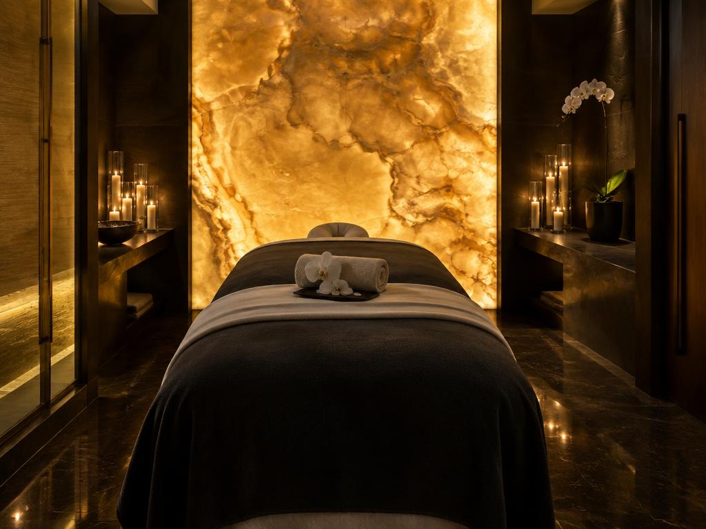 Elegant one-person spa suite with a beige-dressed massage bed, orchid and candlelight